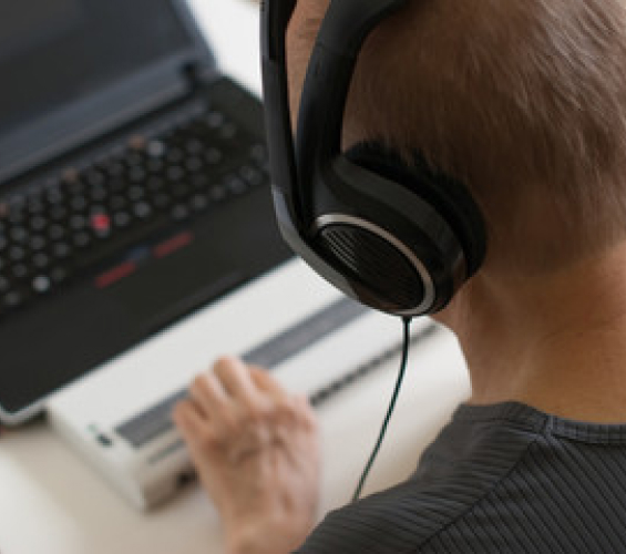 A man wearing headphones uses a laptop.