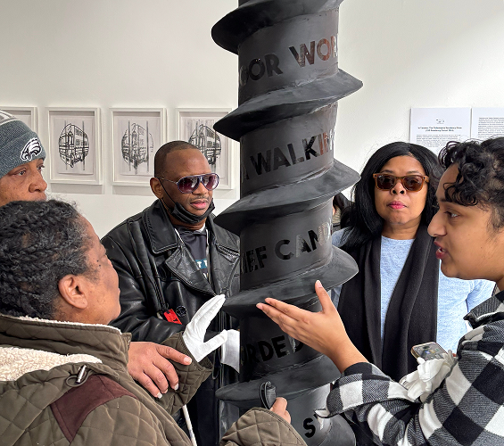 A group explores an Audio Described Art Exhibit at Twelve Gates.