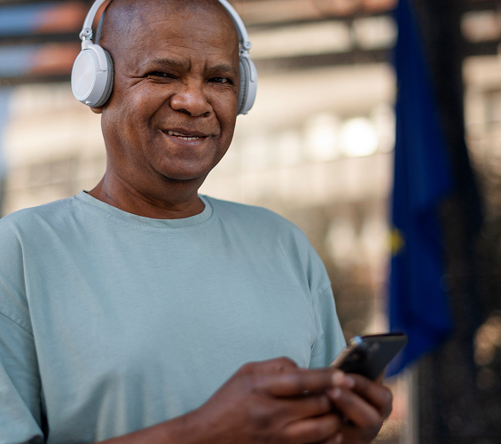 Black man wearing headphones while operating his phone with his hands.