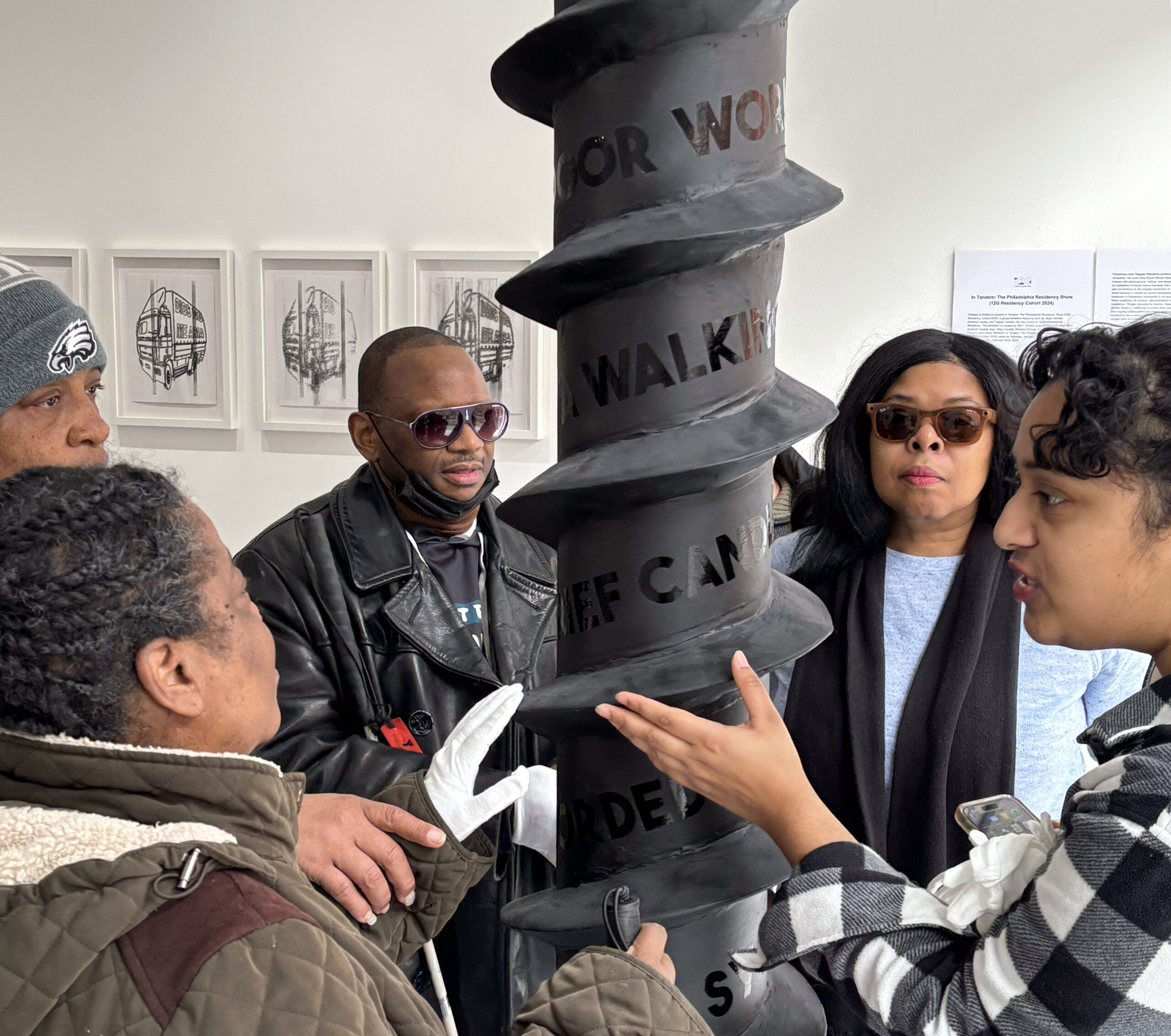 A group of people standing around a sculpture, enjoying an audio described art exhibit at 12 Gates Arts gallery in Philadelphia.