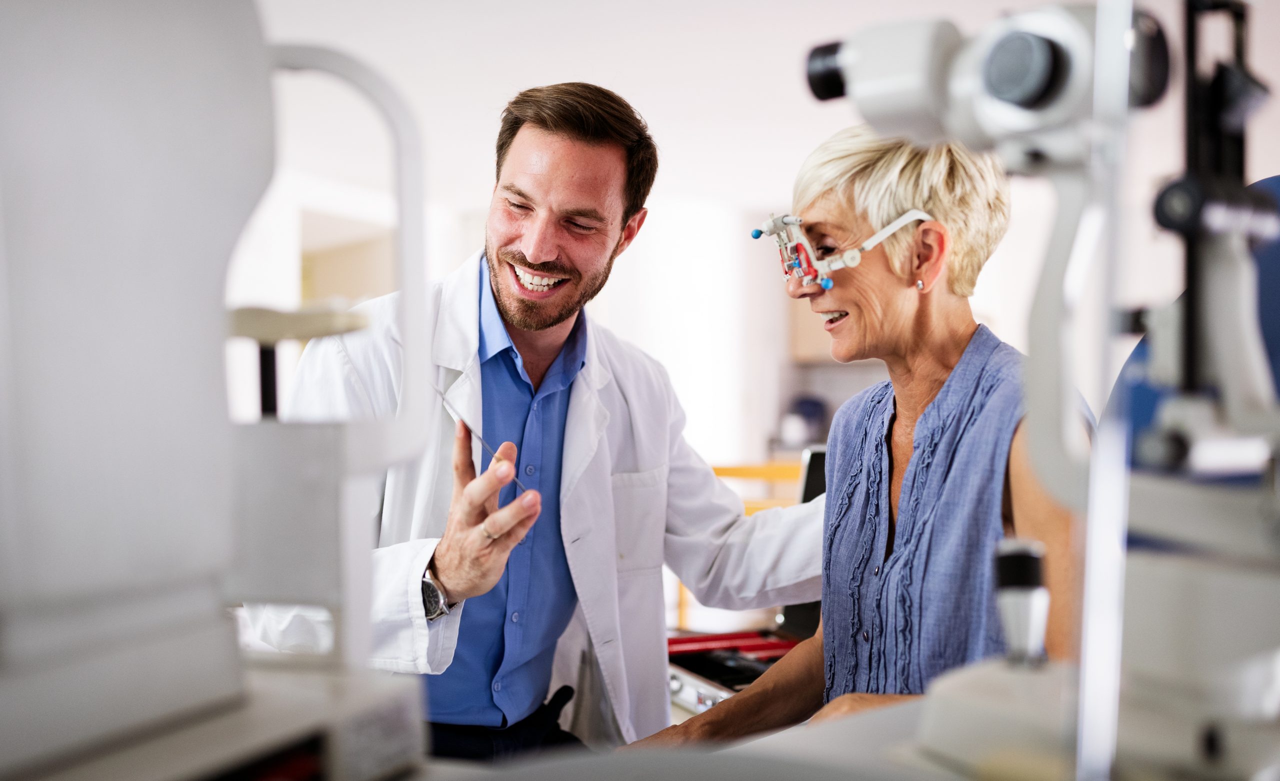 A optometrist helping his patient use trial frames during an examination.