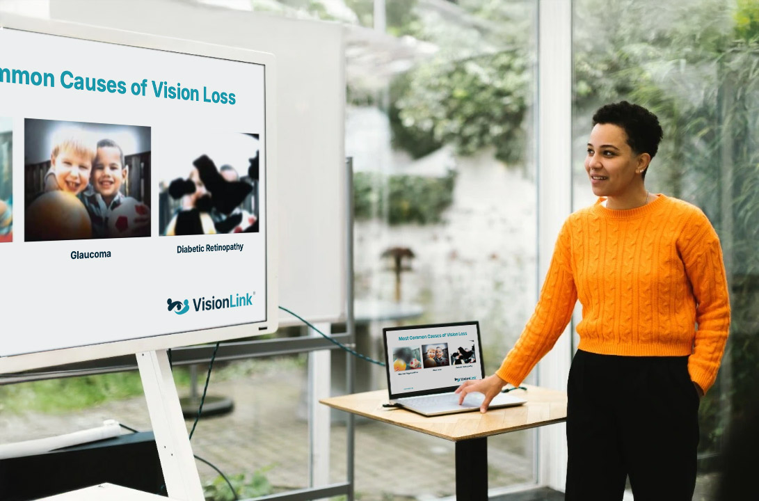 A person stands beside a presentation screen showing "Common Causes of Vision Loss" with images and text about glaucoma and diabetic retinopathy.