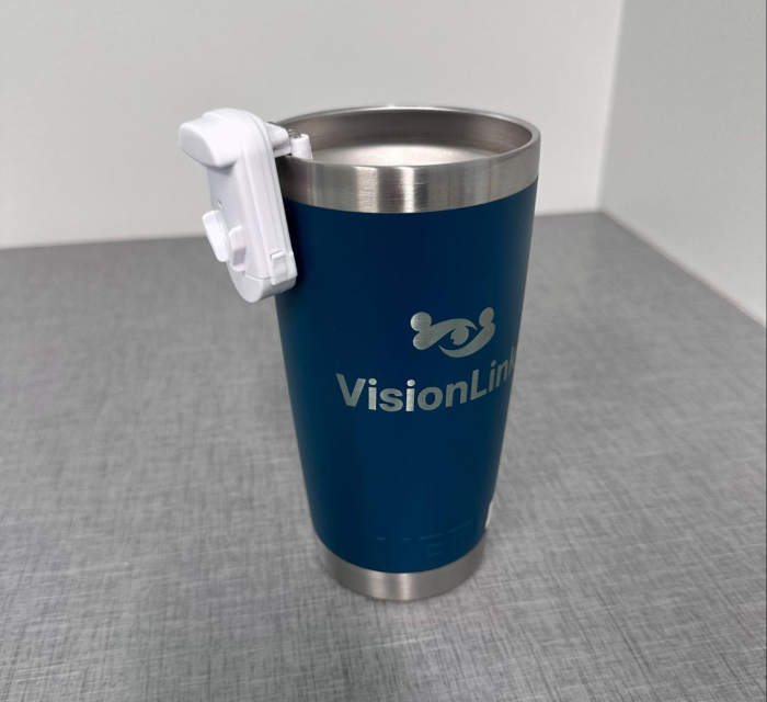 A photo of a liquid level indicator positioned on the rim of a stainless steel, insulated coffee tumbler.