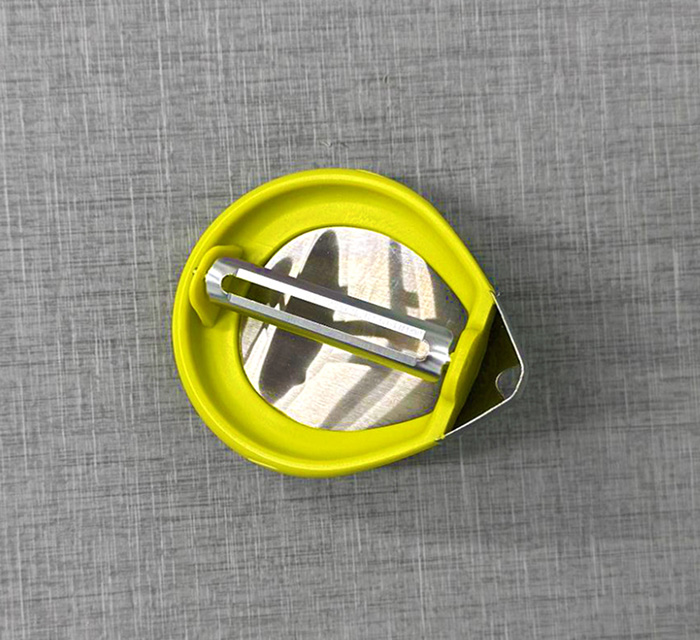 A photo of a round, palm-shaped vegetable peeler.