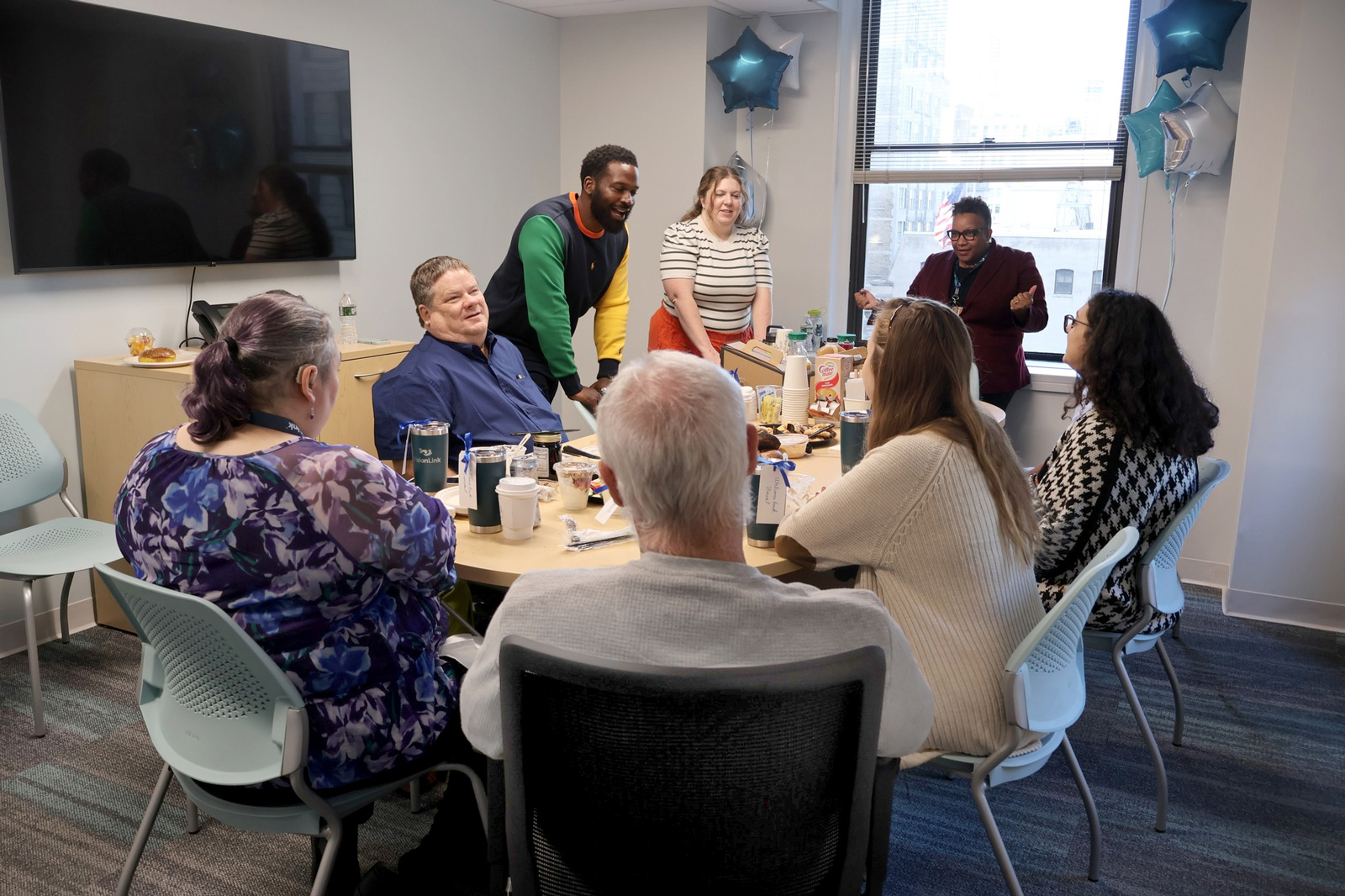 VisionLink staff sitting around a conference table, eating and talking with one another.