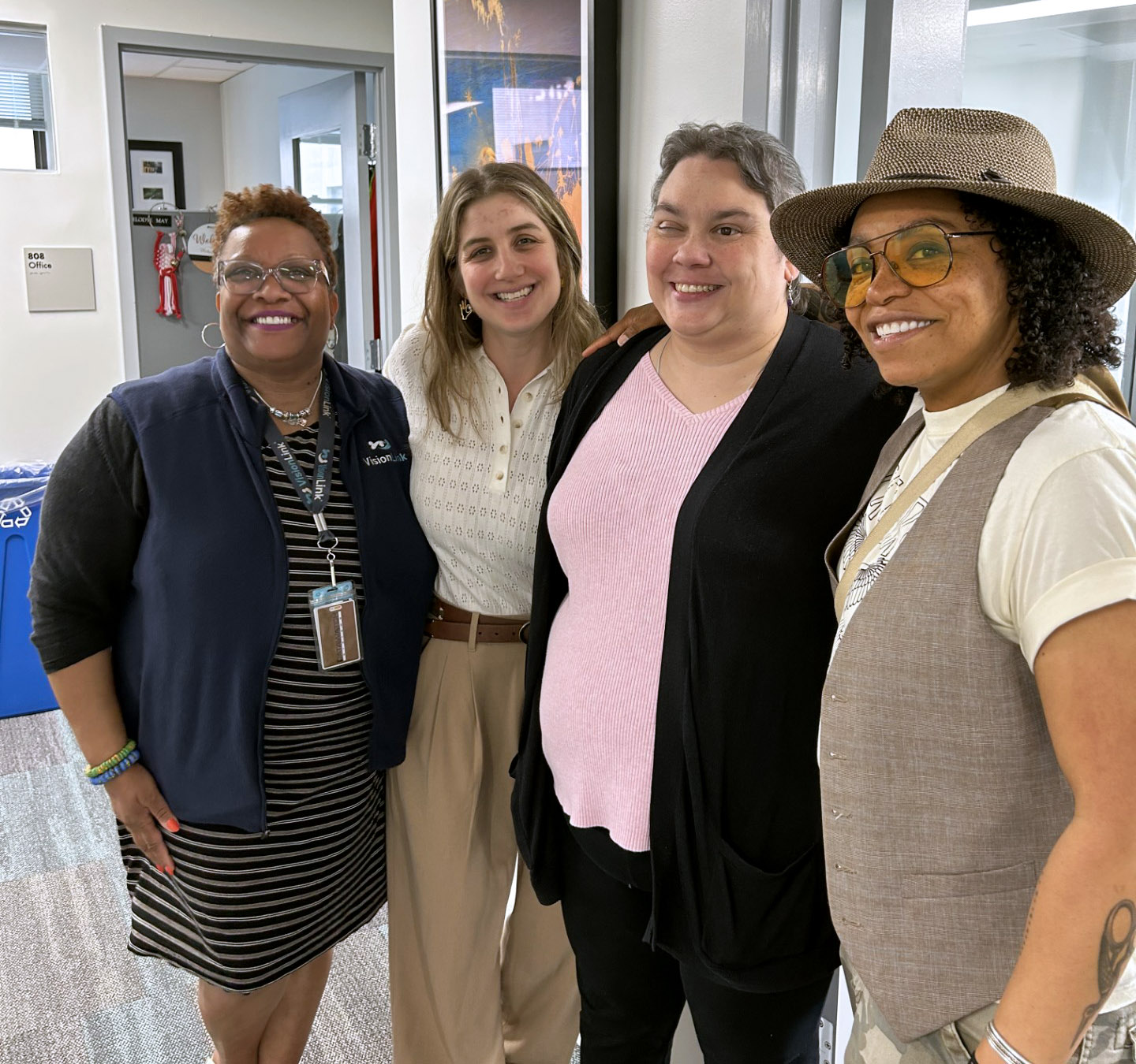 Three VisionLink staff members and podcaster Shara Dae Howard pose together and smile at the VisionLink office.