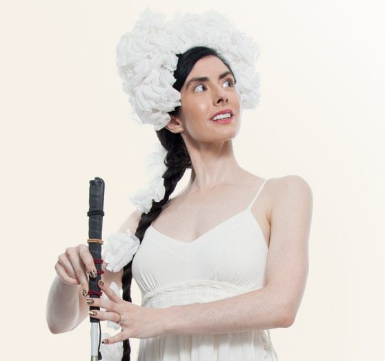 Dancer and Dark Room Ballet founder Krishna Washburn stands in costume with her hands on the handle of a rigid cane.